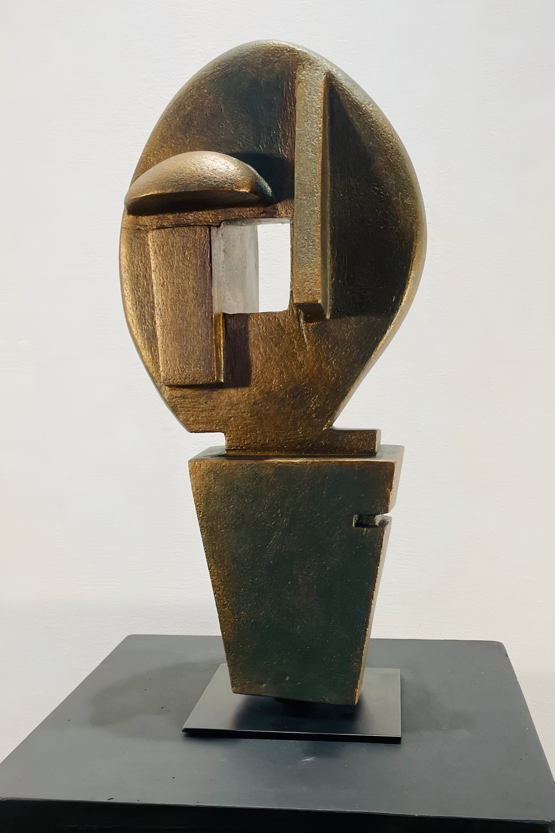 Egg-shaped ceramic head with bronze and moss green geometric planes, rectangular void