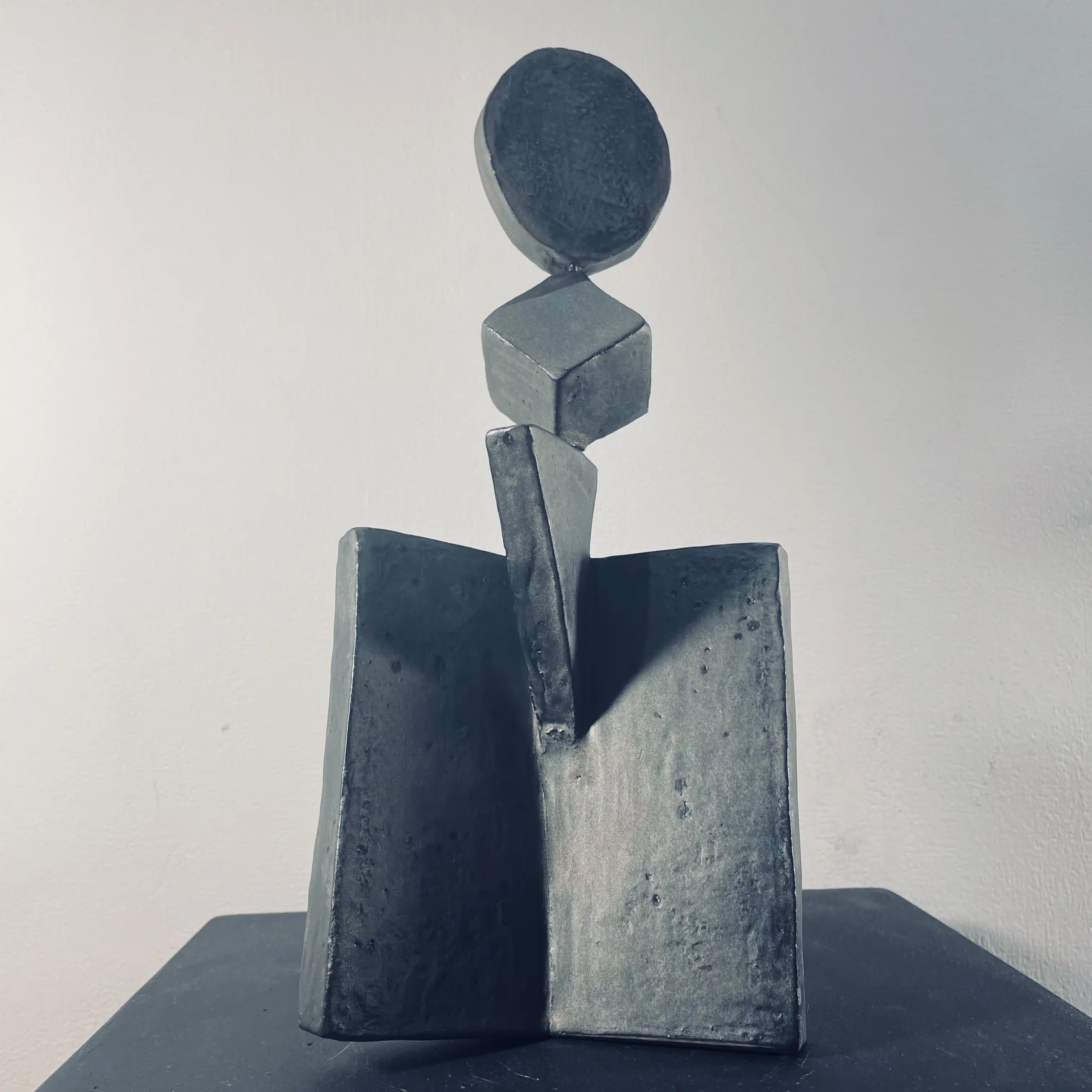 Ceramic sculpture with rhodium enamel: geometric forms stacked above an open book-shaped base