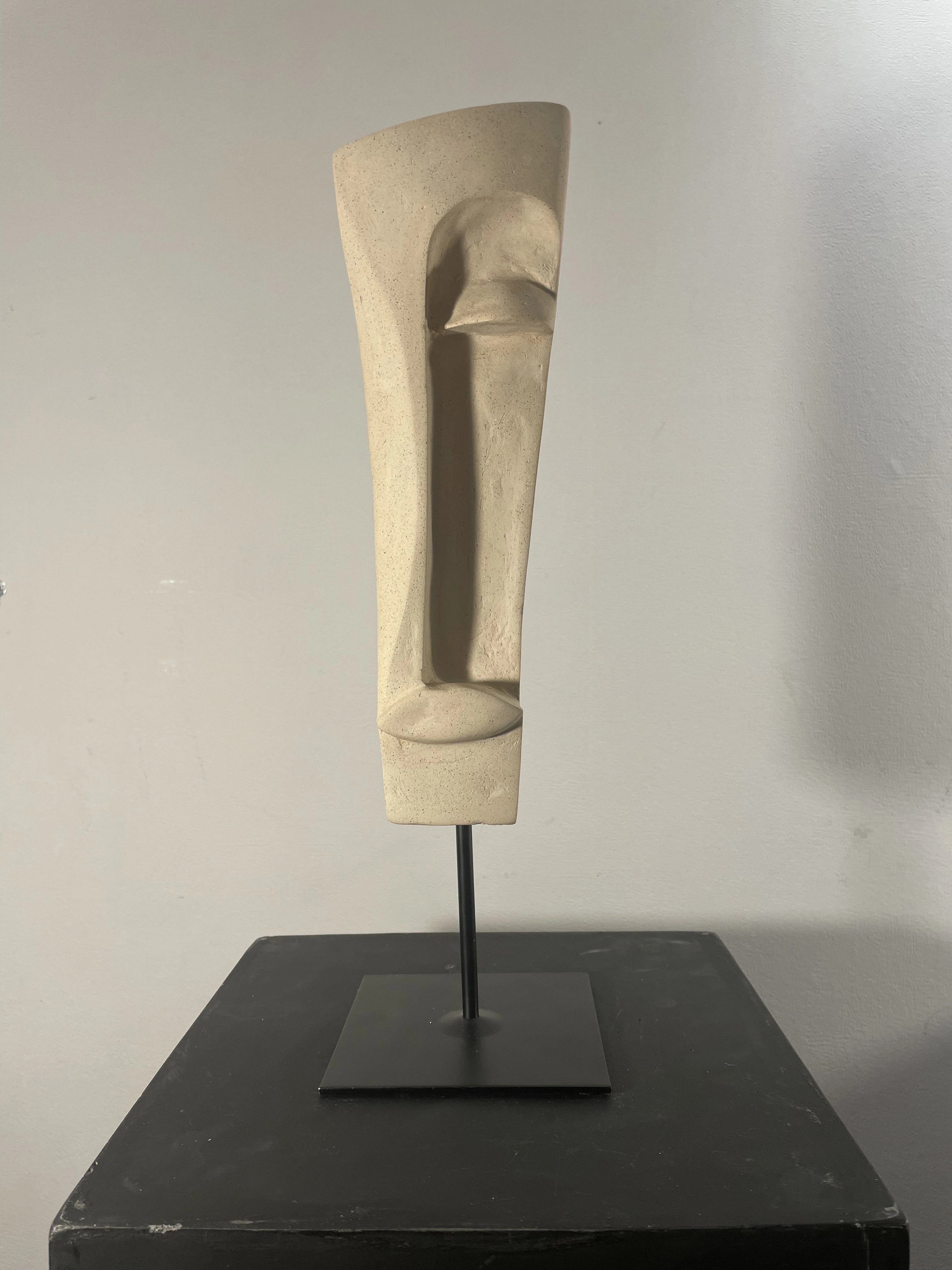 QUIETNESS by Arnaud Quercy at Art Quam Anima — Ceramic Sculpture on Metal, Pale ceramic head with geometric facial planes on dark metal stand: vertical nose blade and horizontal eye slits