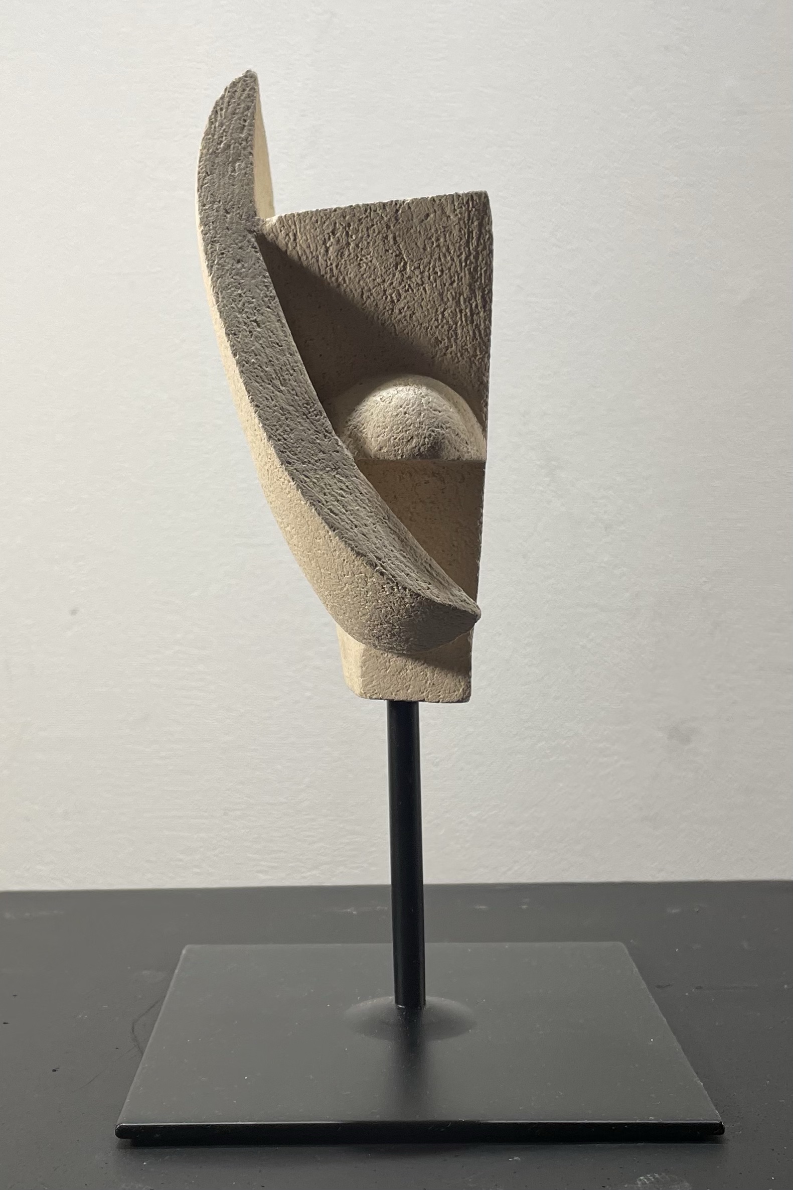 Contemporary ceramic sculpture with curved forms and patina effects mounted on black metal stand